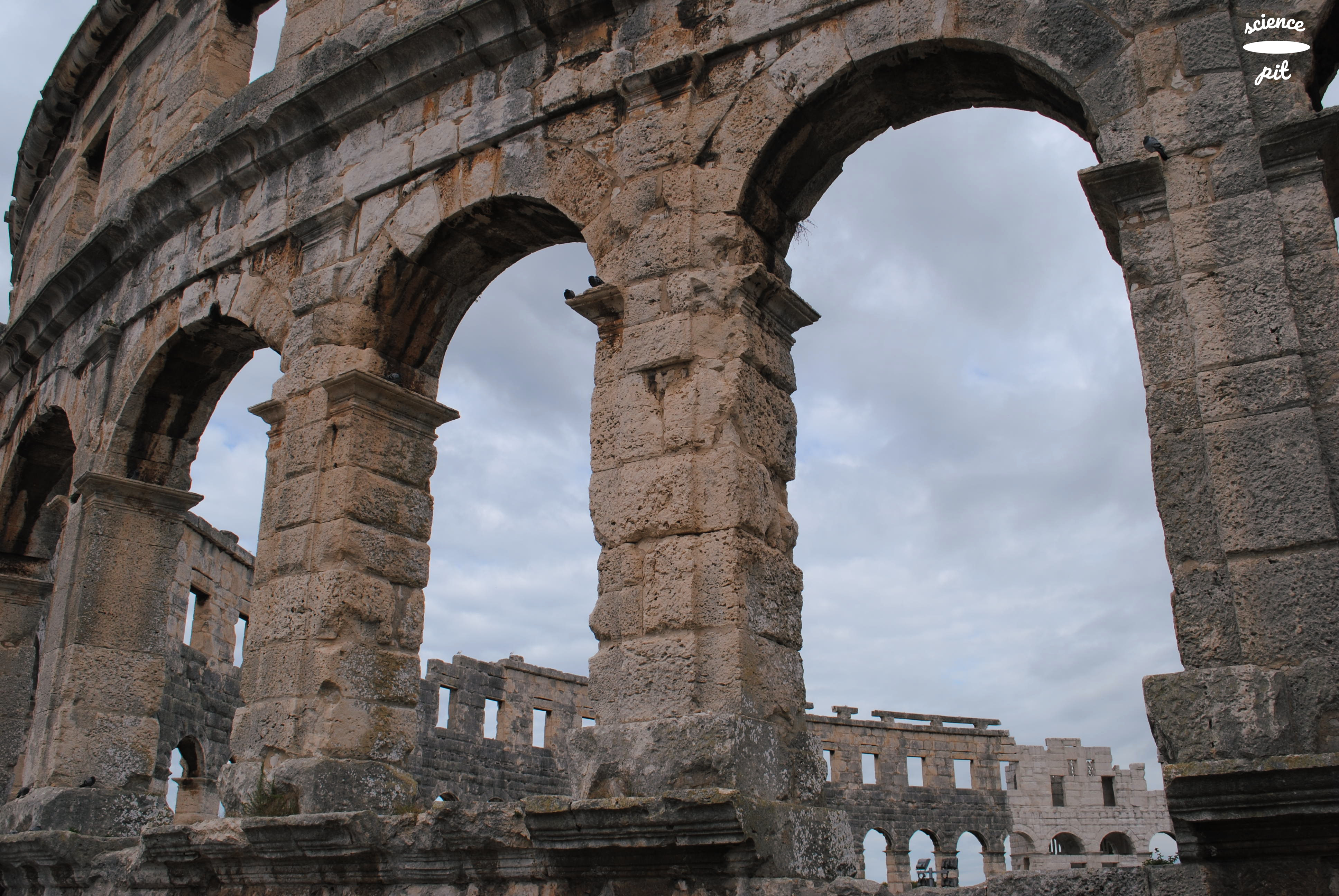 Huge stone arches of Amphitheater in Pula; with sky seen through the arches.